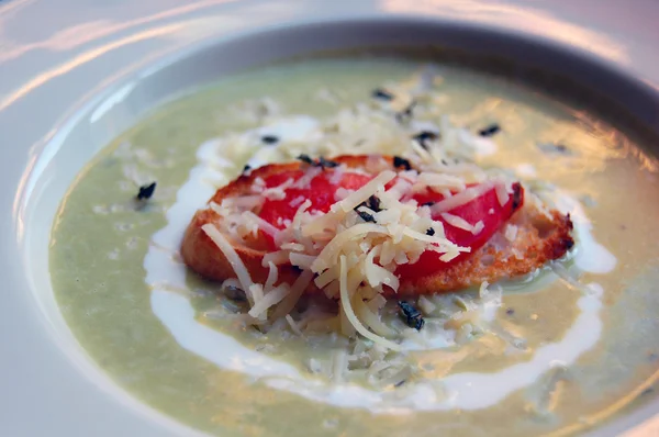 Close up of green pea soup with bread and cheese on top — Stock Photo, Image