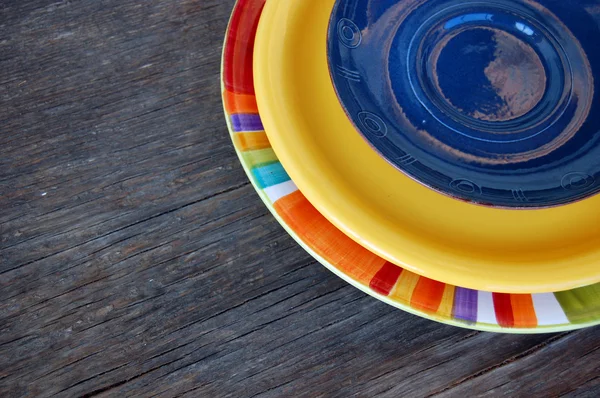 Ahşap arka plan üzerinde renkli tabaklar — Stok fotoğraf