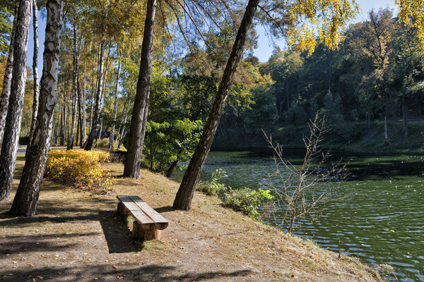 Old wooden bench in a city park with lake