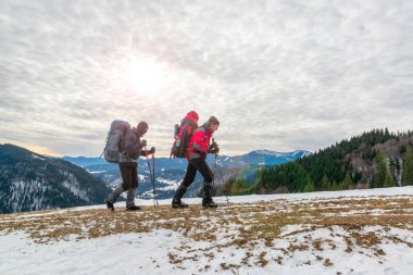 Happy tourists hiking in winter mountains clipart