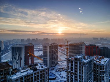 Yeni bir yerleşim bölgesi inşa eden büyük bir inşaat alanının havadan görüntüsü. Güzel kış gündoğumu