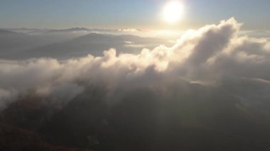Dağların yükseklerinde bulutların arasından uç.