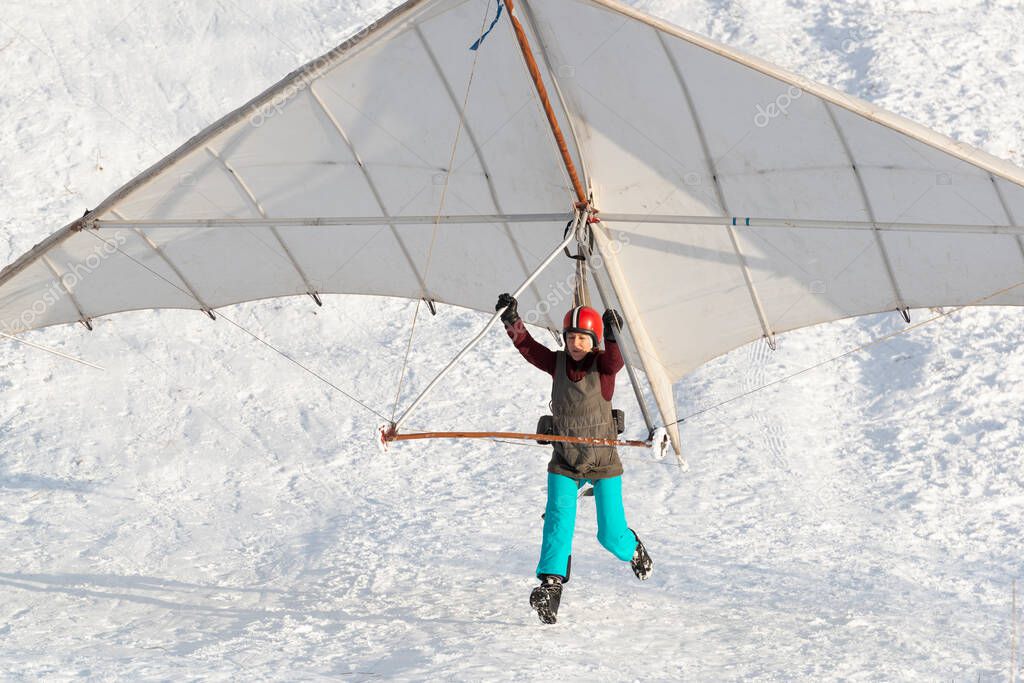 Student girl jumps with a beginner hang glider wing. Learning extreme sports.