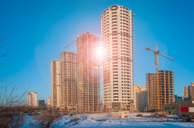 Tamamlanmamış çok katlı binaları ve vinçleri olan bir inşaat alanı. Şehirde genişleme ve büyüme