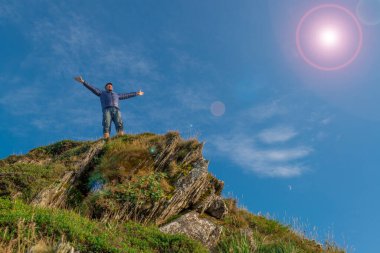 Dağın tepesinde kolları açık bir adam. Mutluluğun, başarının ve mutluluğun sembolü