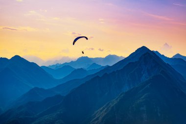 Dağlarda günbatımı rüya uçuşu. İtalya Bordano 'nun gökyüzünde paraglider