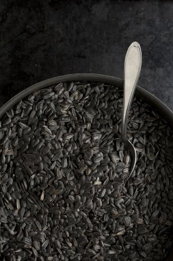 Bir tavada bir kaşık ile siyah ayçiçeği tohumu