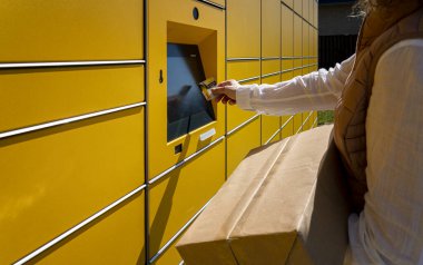 Bir kadın, DHL 'nin tipik sarı Alman paketleme istasyonlarından posta gönderir ve alır.
