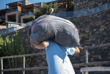 Worker carries a sack on his back clipart