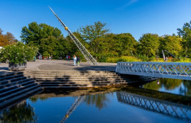 Görüntü, güneşli bir sonbahar gününde Britzer Bahçesi 'nin beyaz ahşap tavanını gösteriyor. Aşağıdaki suya açıkça yansıyor. Güneşli sonbahar günü, Berlin, Almanya
