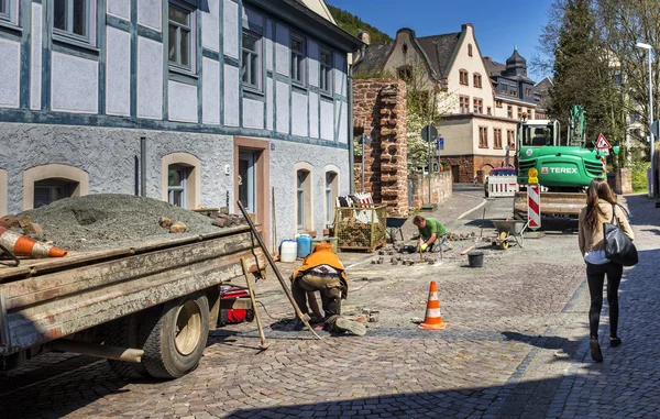 Trabajadores de la construcción reparan una carretera en un pequeño pueblo —  Fotos de Stock
