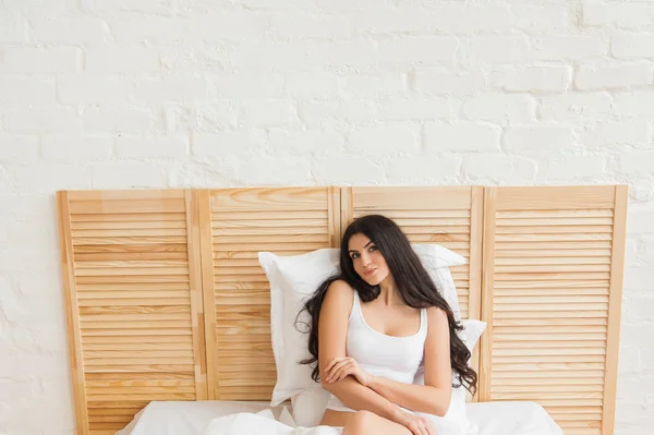 Sexy Mädchen sitzt in Unterwäsche auf dem weißen Bett — Stockfoto