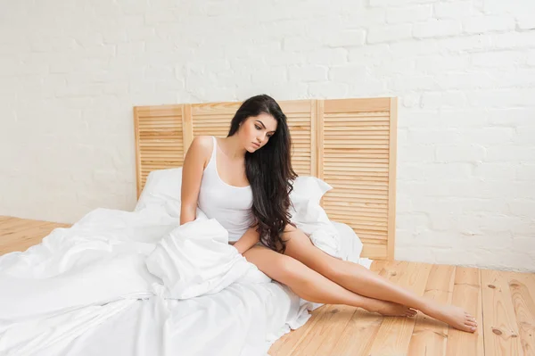 Mujer molesta sentada en el borde de la cama en el dormitorio — Foto de Stock