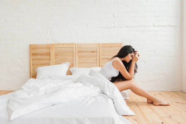 Mujer molesta sentada en el borde de la cama en el dormitorio — Foto de Stock