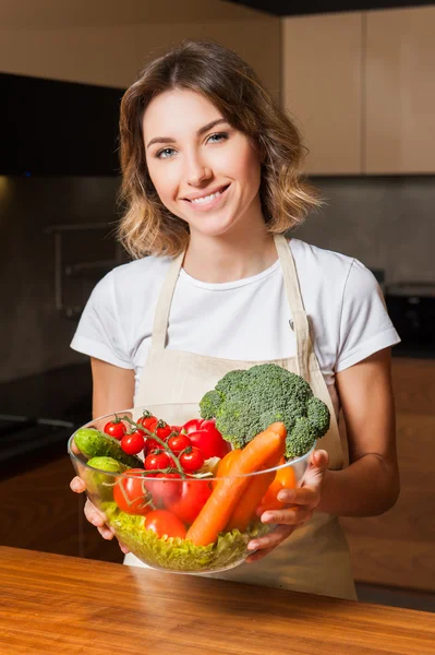 Mutfakta tabak salata tutan genç kadın resim