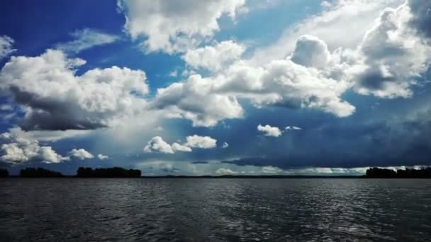 Paisaje tranquilo del lago con aguas tranquilas y nubes blancas en el cielo azul — Vídeos de Stock