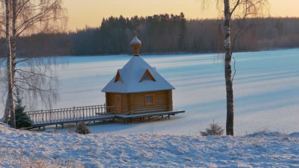 日当たりの良い雪の降る冬の日に小さな木造礼拝堂 — ストック動画