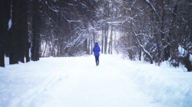 Bir kenara snowdrifts ve yürüyen kadın olan yol