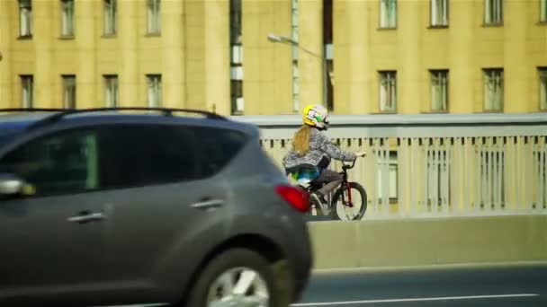 Chica en casco pasando auto puente en bicicleta — Vídeos de Stock