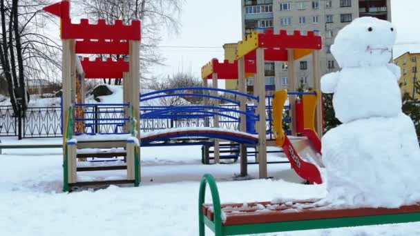 Boneco de neve no parque infantil após queda de neve pesada — Vídeo de Stock