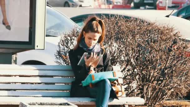 매력적인 젊은 여 자가 Elecrtonic 책을 읽고는 벤치에 앉아 — 비디오
