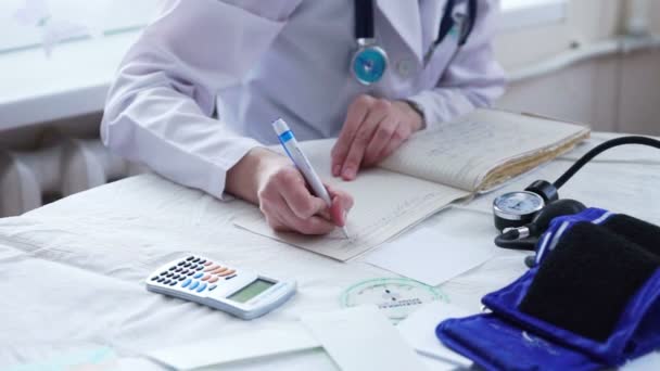 Arts handen in wit uniforme schrijven voorschrift aan een patiënt — Stockvideo
