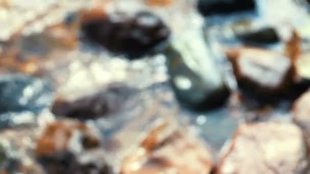 Salpicaduras de agua desenfocadas a las piedras en la orilla del lago — Vídeos de Stock