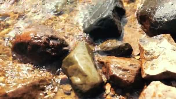 Víz fröccsenés, hogy a köveket a tó partján — Stock videók