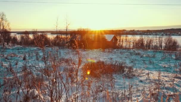 Houten huis op de oever van het meer van een Snowy in zonsondergang in de Winter — Stockvideo