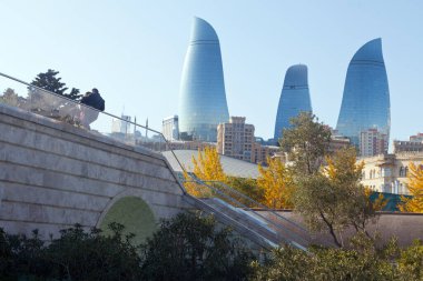 Bakü Bulvarı 'ndan Alev Kuleleri' ne kadar üç modern gökdelen ve köprüde birbirine aşık bir çift. Bakü, Azerbaycan - Kasım 2019