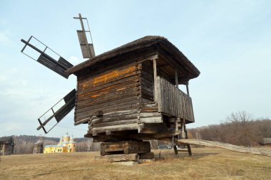 Siluet antik yel değirmeni kırsal alan ve arka plandaki kilise. Ulusal Açık Hava Halk Mimarisi Müzesi Pirogovo. Ukrayna, Kiev, Mart 08, 2019