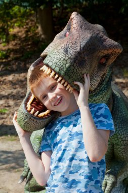 Yeniden yapılandırılmış gerçek boyutlarda bir dinozorun animasyon modeliyle oynayan çocuk. Ukrayna 'daki en büyük dinozorlar, Uman.