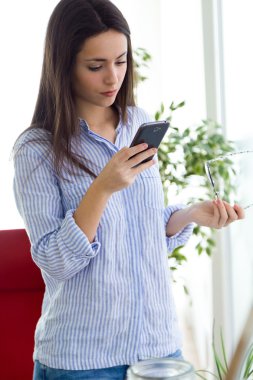 Ofiste cep telefonu kullanan iş genç kadın.