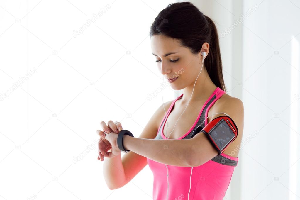 Young fitness woman looking at her smart watch while taking a br
