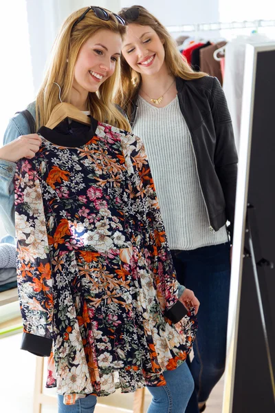 Två vackra unga kvinnor shopping i en klädaffär. — Stockfoto