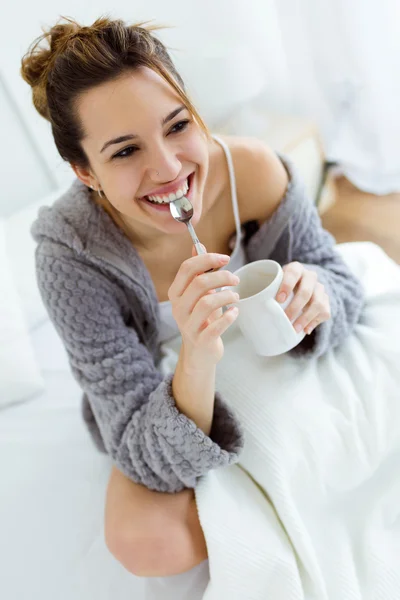 Schöne junge Frau trinkt Kaffee auf dem Bett. — Stockfoto