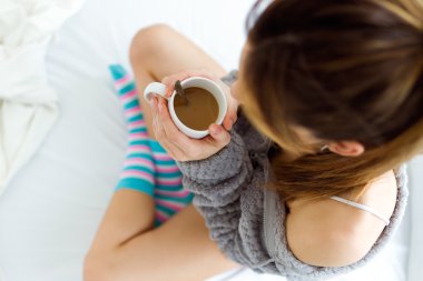 Güzel genç kadın yatakta kahve içme.