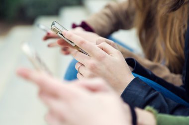 Sokakta bir cep telefonu kullanarak üç genç kadın.