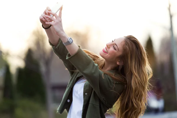 Krásná mladá žena pomocí svého mobilního telefonu na ulici. — Stock fotografie