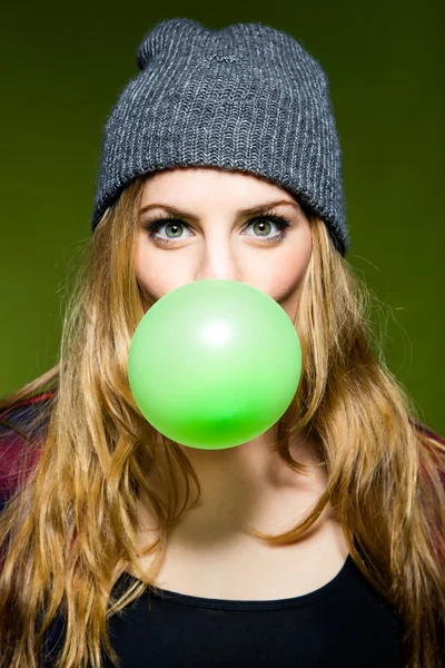 Belle jeune femme soufflant du bubblegum vert. Isolé . — Photo