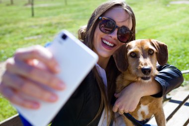 Cep telefonu kullaranarak köpeğini olan güzel kadın.