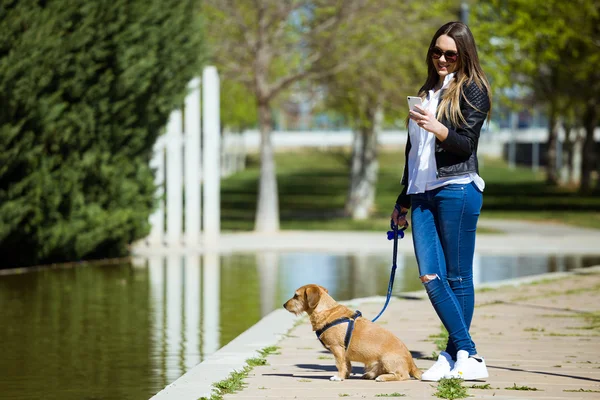 Красивая молодая женщина со своей собакой с помощью мобильного телефона . — стоковое фото