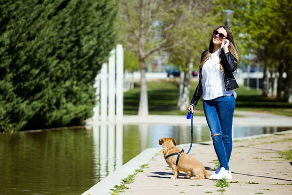 Smuk ung kvinde med sin hund ved hjælp af mobiltelefon . - Stock-foto