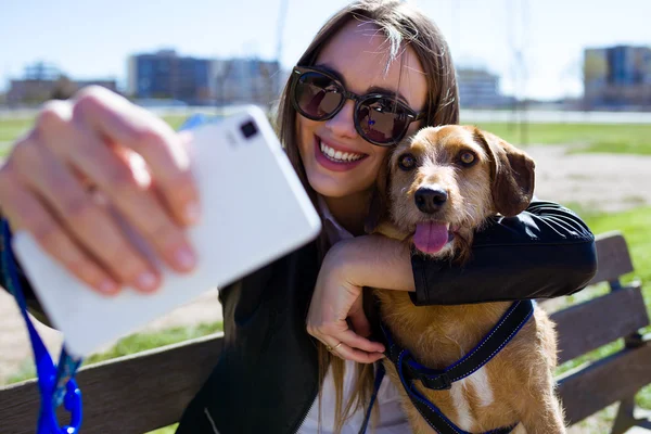 美丽的年轻女子，与她的狗使用手机. — 图库照片
