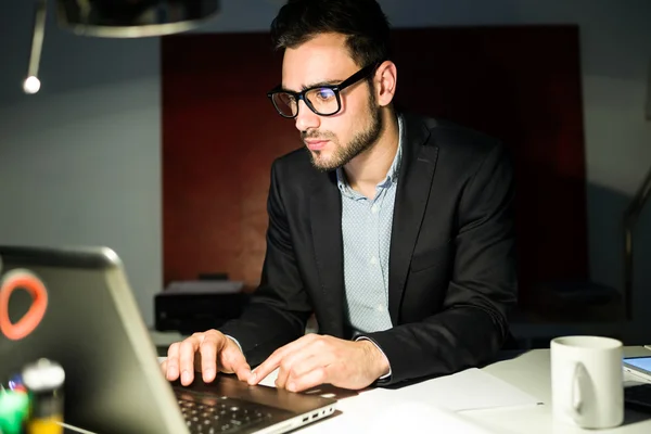 Bonito jovem empresário trabalhando com laptop no escritório . — Fotografia de Stock