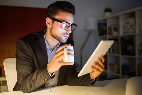 Красивый молодой человек, работающий с цифровым планшетом в офисе . — стоковое фото
