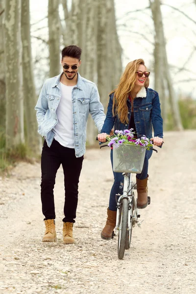 Beautiful young couple in love on bike in the park. — Stock Photo, Image