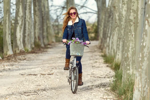 Красива молода жінка катається на велосипеді в парку . — стокове фото