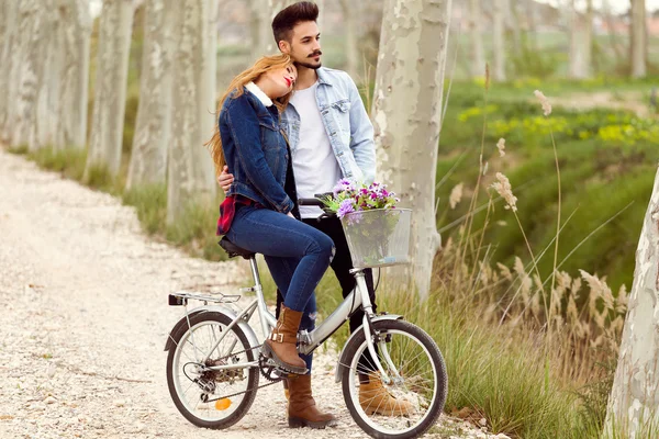 Hermosa pareja joven enamorada en bicicleta en el parque . — Foto de Stock