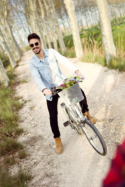 Knappe jongeman fietsen in het park. — Stockfoto